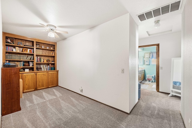 office with light carpet, attic access, baseboards, visible vents, and a ceiling fan