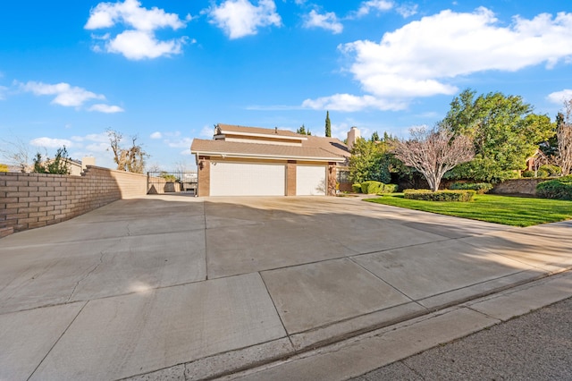 exterior space with concrete driveway, a front yard, and fence