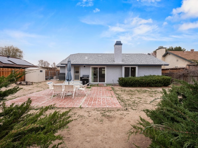 back of house with stucco siding, an outbuilding, a fenced backyard, a shed, and a patio area