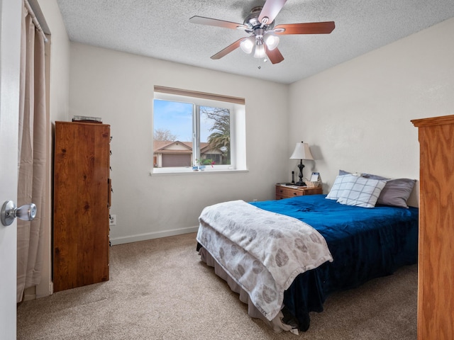 carpeted bedroom with a ceiling fan, baseboards, and a textured ceiling