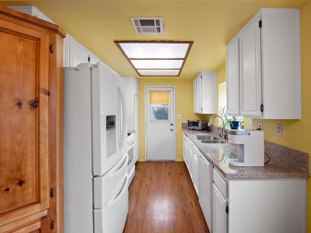 kitchen featuring white appliances, visible vents, a sink, white cabinets, and light wood-style floors