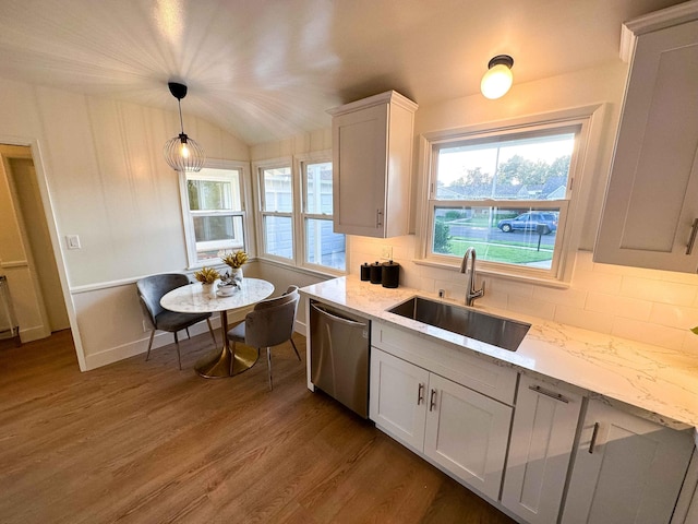 kitchen with tasteful backsplash, light stone counters, wood finished floors, a sink, and stainless steel dishwasher