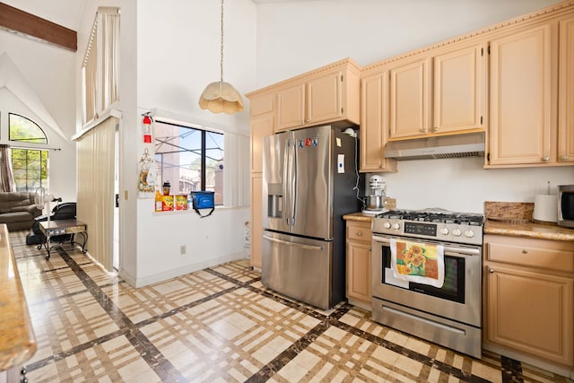 kitchen featuring light brown cabinetry, hanging light fixtures, high vaulted ceiling, and appliances with stainless steel finishes