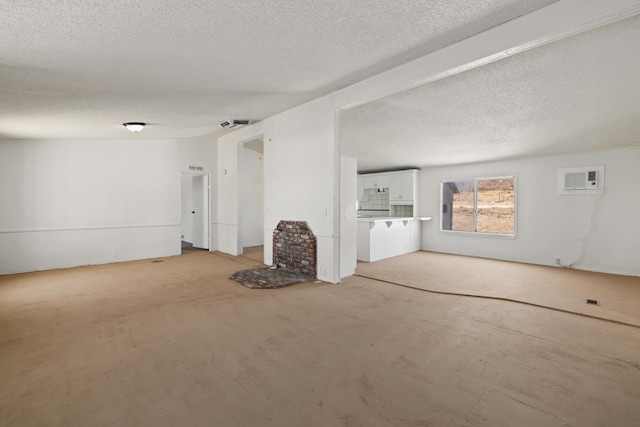 23610 Lancaster Rd, Lancaster, CA 93536 - unfurnished living room featuring a wall mounted air conditioner and a textured ceiling
