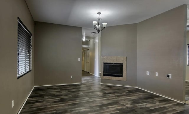 unfurnished living room with a chandelier and dark hardwood / wood-style floors