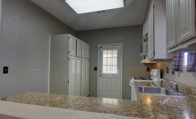 kitchen featuring white cabinets, white range, and sink