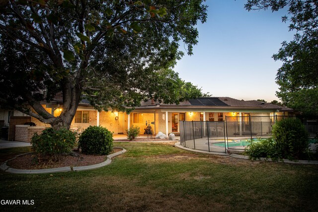 43710 Shiloh Ln, Lancaster, CA 93535 - rear view of house featuring solar panels and a lawn