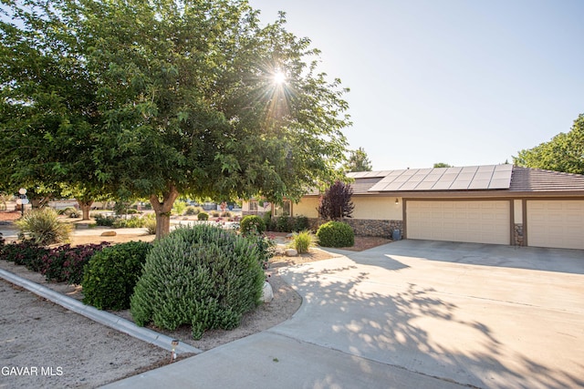 43710 Shiloh Ln, Lancaster, CA 93535 - view of front facade featuring driveway, a garage, solar panels, stucco siding, and stone siding