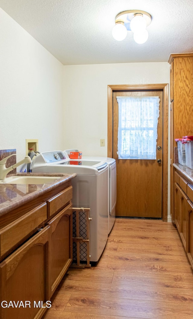 43710 Shiloh Ln, Lancaster, CA 93535 - laundry area featuring separate washer and dryer, cabinet space, light wood finished floors, and a textured ceiling