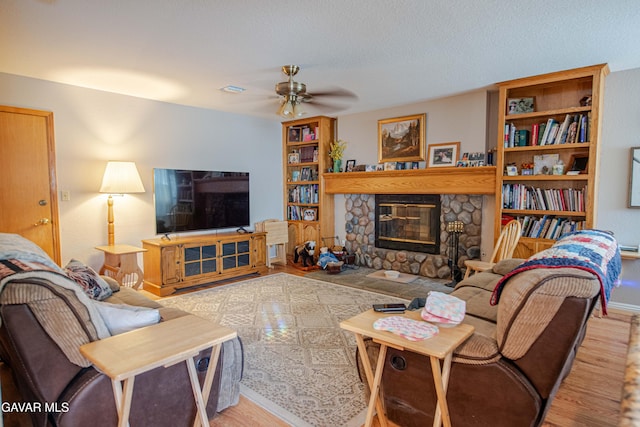 43710 Shiloh Ln, Lancaster, CA 93535 - living room featuring wood finished floors, ceiling fan, and a stone fireplace