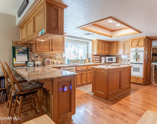 43710 Shiloh Ln, Lancaster, CA 93535 - kitchen with white appliances, a textured ceiling, a tray ceiling, a peninsula, and backsplash