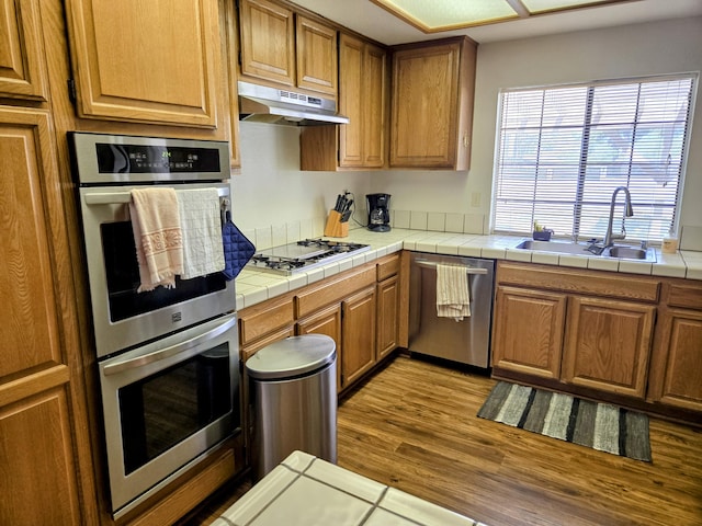 35823 E 48th St, Palmdale, CA 93552 - kitchen featuring appliances with stainless steel finishes, under cabinet range hood, a sink, wood finished floors, and brown cabinets
