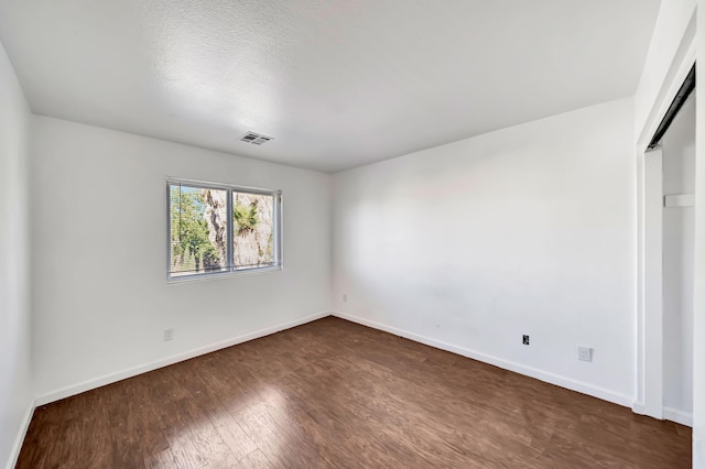 unfurnished bedroom with a textured ceiling, dark wood-type flooring, and a closet