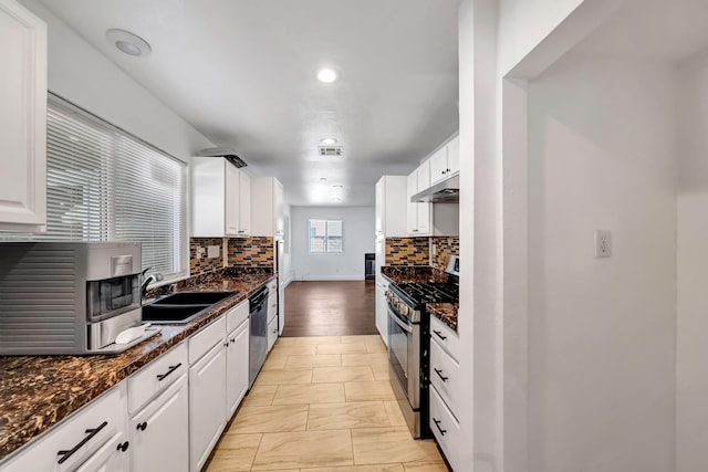 kitchen featuring white cabinets, appliances with stainless steel finishes, sink, and dark stone countertops