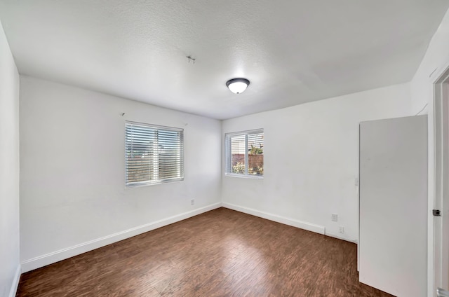 unfurnished room with a textured ceiling and dark hardwood / wood-style floors