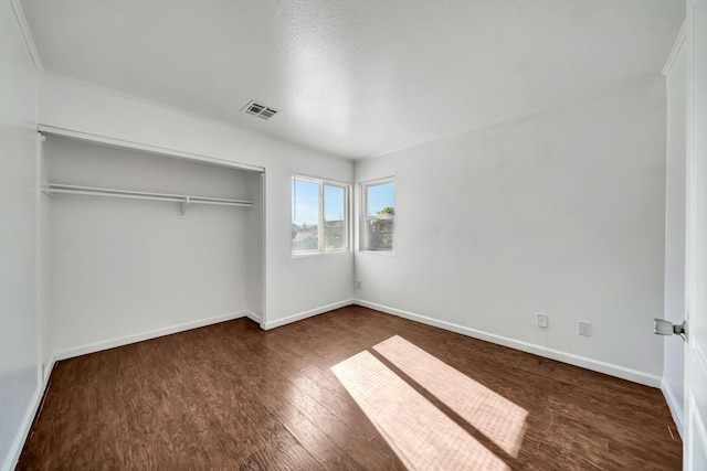 unfurnished bedroom with a closet and dark wood-type flooring