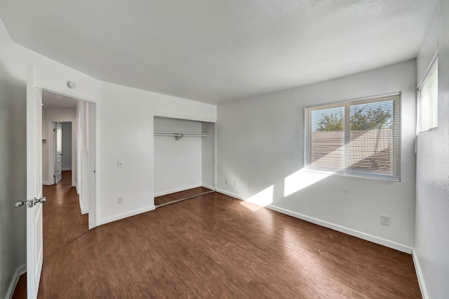 unfurnished bedroom with dark hardwood / wood-style floors and a closet