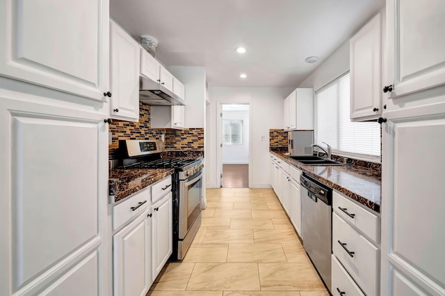 kitchen featuring sink, dark stone countertops, light tile patterned floors, appliances with stainless steel finishes, and white cabinetry