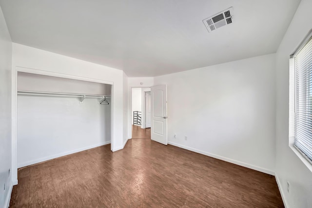 unfurnished bedroom with dark hardwood / wood-style floors and a closet