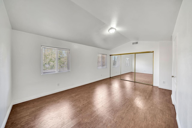 unfurnished bedroom featuring dark hardwood / wood-style flooring, a closet, and lofted ceiling