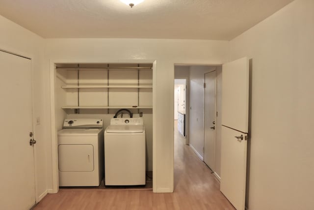 clothes washing area featuring washer and dryer and light wood-type flooring