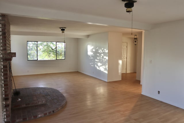 spare room with a fireplace, hardwood / wood-style floors, and beam ceiling