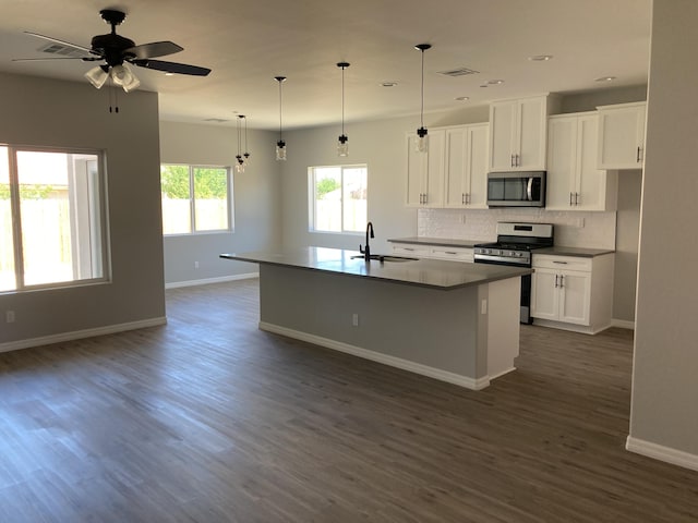 kitchen with sink, hanging light fixtures, appliances with stainless steel finishes, an island with sink, and white cabinets