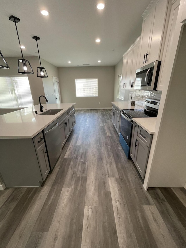 kitchen with decorative light fixtures, sink, gray cabinetry, stainless steel appliances, and dark wood-type flooring