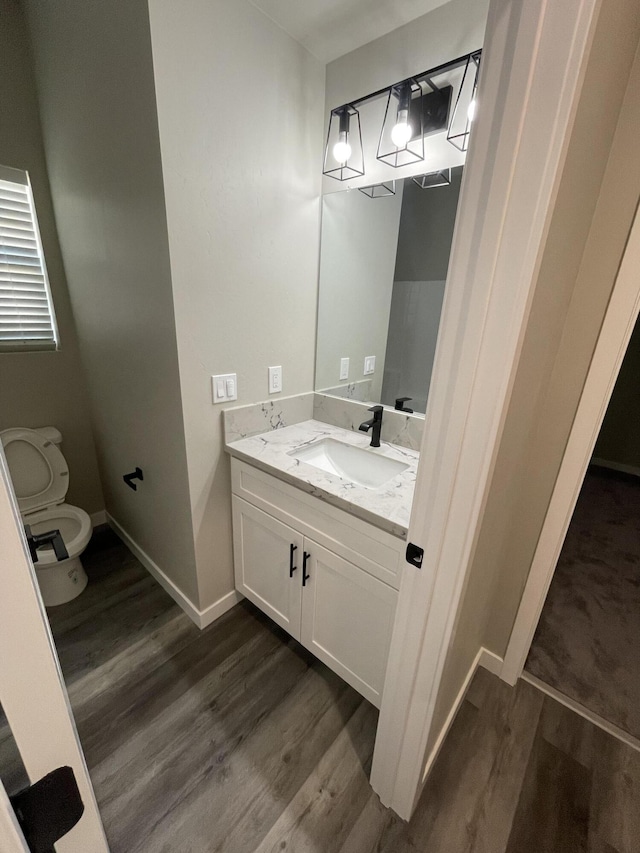 bathroom with hardwood / wood-style flooring, vanity, and toilet