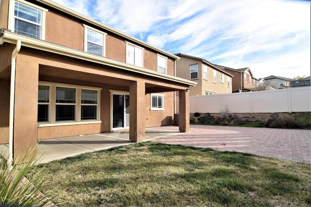 rear view of house featuring a patio area and a lawn