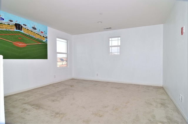 unfurnished room featuring plenty of natural light and light carpet