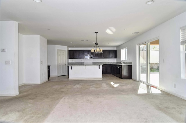 kitchen with a kitchen bar, dark brown cabinetry, sink, hanging light fixtures, and a kitchen island