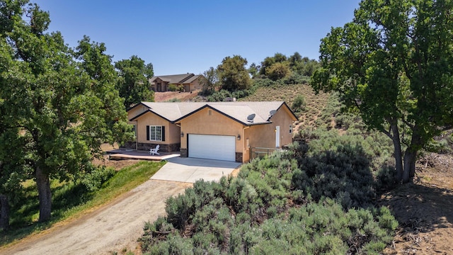 24481 Jacaranda Dr, Tehachapi, CA 93561 - view of front facade featuring driveway, an attached garage, stone siding, and stucco siding