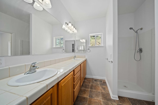24481 Jacaranda Dr, Tehachapi, CA 93561 - bathroom with double vanity, a tile shower, baseboards, and stone finish flooring