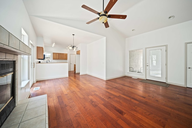 24481 Jacaranda Dr, Tehachapi, CA 93561 - unfurnished living room with a chandelier, a ceiling fan, wood finished floors, high vaulted ceiling, and a sink
