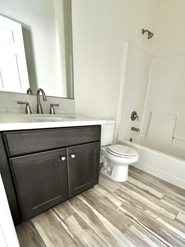 full bathroom with washtub / shower combination, hardwood / wood-style floors, vanity, and toilet