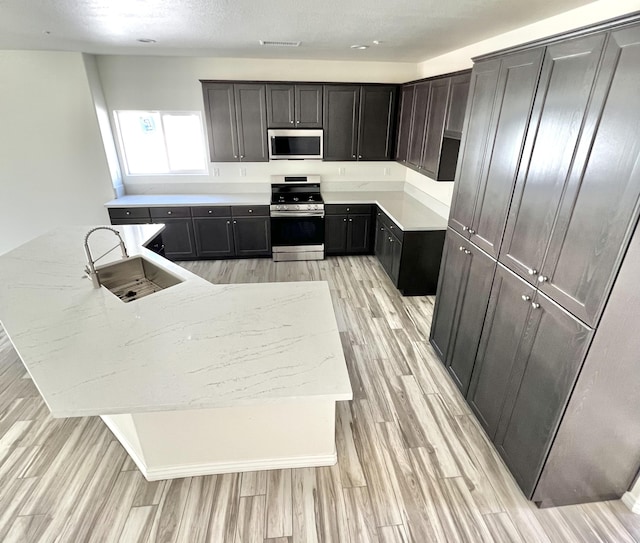 kitchen featuring light stone countertops, range, light hardwood / wood-style floors, and sink