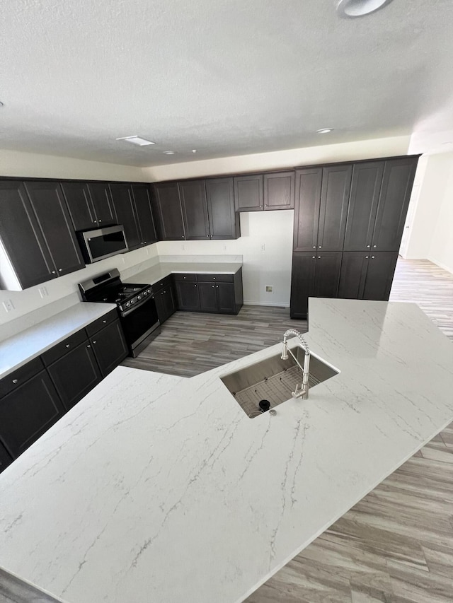 kitchen featuring stove, light hardwood / wood-style flooring, and sink