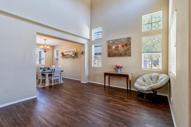 sitting room featuring dark hardwood / wood-style flooring, a high ceiling, and an inviting chandelier