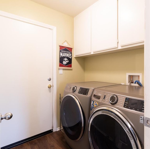 clothes washing area with cabinets, washer and clothes dryer, and dark wood-type flooring