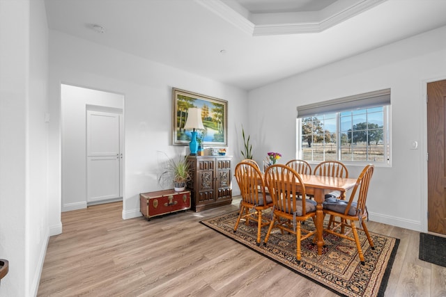 dining space featuring a raised ceiling and light wood-type flooring