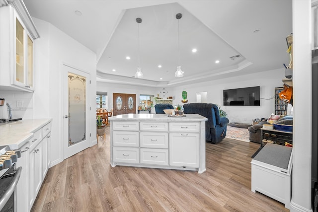 kitchen with white cabinetry, light hardwood / wood-style flooring, pendant lighting, stainless steel electric range, and a tray ceiling