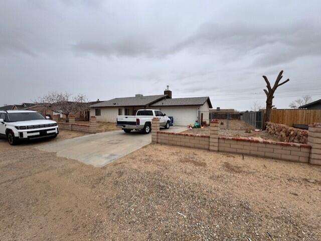 view of front of property featuring concrete driveway and fence