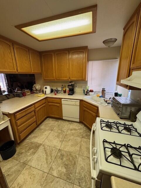 kitchen with light countertops, brown cabinets, and white appliances
