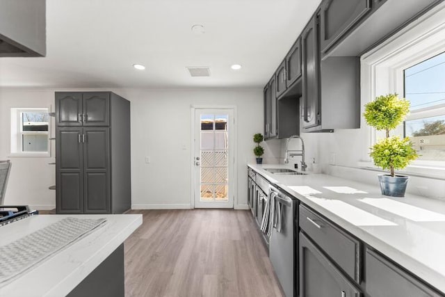 kitchen with a wealth of natural light, sink, stainless steel dishwasher, and light wood-type flooring