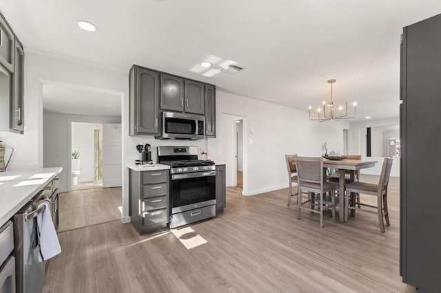 kitchen with appliances with stainless steel finishes, decorative light fixtures, a notable chandelier, crown molding, and light wood-type flooring