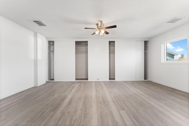 unfurnished bedroom with ceiling fan, light hardwood / wood-style flooring, and two closets