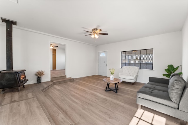 living room featuring light wood-type flooring, ceiling fan, and a wood stove