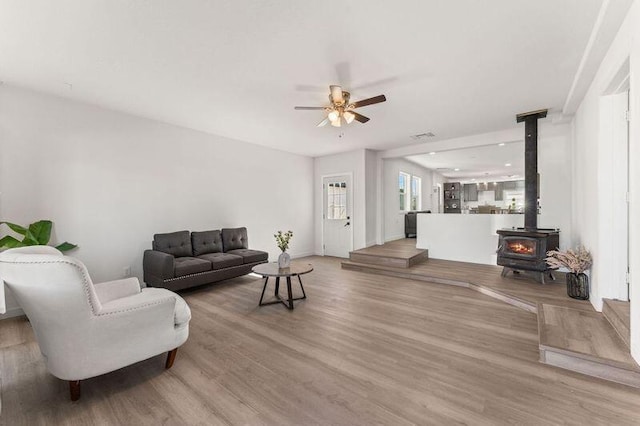 living room with hardwood / wood-style floors, ceiling fan, and a wood stove