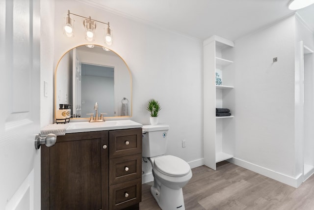 bathroom featuring ornamental molding, wood-type flooring, toilet, and vanity